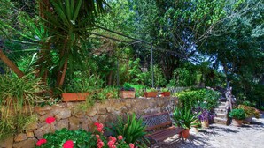 Un muro di pietra con piante in vaso e una panchina in un giardino.