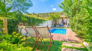 Ein Garten mit Schwimmbad, Holzterrasse und Sitzbereich mit Stühlen und Tisch.