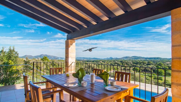 Ein Esstisch, gedeckt für ein Essen, mit Blick auf Berge und einen Pool.