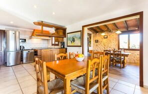 A kitchen with modern appliances, a dining area with wooden furniture, and a stone wall in the background. - Stunning home in Cala dOr with private swimming pool, can be inside or outside (Cala dOr)