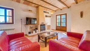 Ein Wohnzimmer mit roten Ledersofas, einem Fernseher, einem Kamin und einem Bücherregal.