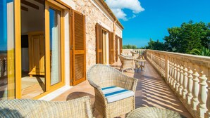 A balcony with wicker furniture, a stone wall, and a view of greenery. - Can Ferragut de Porto Cristo (Porto Cristo)