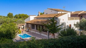 Une villa avec piscine, entourée d’une végétation luxuriante et sous un ciel d’un bleu éclatant.