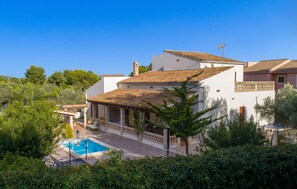 Une villa avec piscine, entourée d’une végétation luxuriante et sous un ciel d’un bleu éclatant.