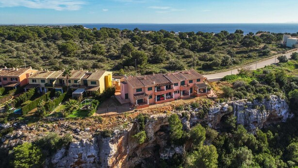Un área residencial costera con casas escalonadas, vista despejada al mar y acantilados rocosos.