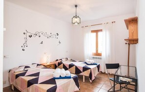 Ein Hotelzimmer mit zwei Betten, einem Schreibtisch, einem Stuhl, einem Fenster mit Vorhängen, einem Heizkörper und einer Wanddekoration.