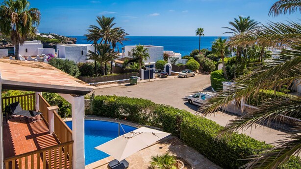Ein Wohngebiet mit Pool, weißen Gebäuden und Blick auf das Meer.