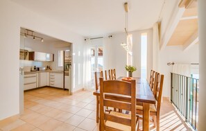 A spacious kitchen with modern appliances, a dining area with wooden chairs, and a balcony with a railing. - Awesome home in Canyamel with private swimming pool, can be inside or outside (Canyamel)