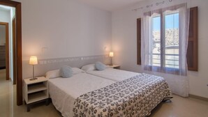 A bedroom with two beds, a nightstand with a lamp, a window with curtains, and a view of the outside. - 4 bedroom amazing home in Buger (Buger)