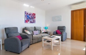 Ein modernes Wohnzimmer mit grauen Sofas, einem weißen Couchtisch und einer Holztür.