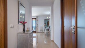 A hallway with a wooden door, a mirror, a vase with flowers, and a dining area in the background. - 4 bedroom amazing home in Buger (Buger)