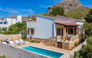 A modern villa with a swimming pool, stone walls, and a mountain backdrop. - Beach front home in Colonia de Sant Pere (Colonia de Sant Pere)
