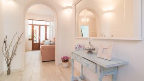 A hallway with a pink sofa, a white console table with decorative items, and a large mirror. - 3 bedroom cozy home in Alcudia (Alcudia)
