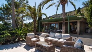 Un'area relax all'aperto con mobili in vimini e una veranda coperta.