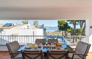 Varanda com mesa posta para café da manhã, com vista panorâmica para um corpo de água e edifícios.
