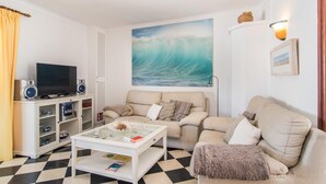 Una sala de estar con un cuadro grande de una ola, un televisor y un sofá.