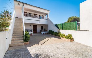 Uma casa de dois andares com varanda, alpendre coberto e entrada com calçada.