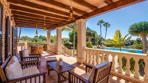 A covered outdoor seating area with wooden furniture and a view of a swimming pool and palm trees. - Lovely home in SHorta with private swimming pool, can be inside or outside (SHorta)
