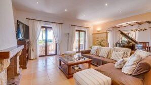 A spacious living room with a sofa, ottoman, and a piano. There is a television on a stand and a sliding glass door leading to an outdoor area. - Lovely home in SHorta with private swimming pool, can be inside or outside (SHorta)