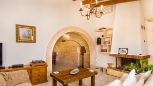Un salon doté d’une cheminée, de meubles en bois et d’une porte en arc donnant sur une autre pièce.