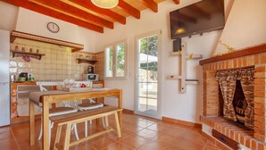 Una cocina con una mesa y sillas de madera, un televisor montado en la pared y una chimenea de ladrillo.