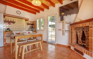 A kitchen with a wooden table and chairs, a TV mounted on the wall, and a brick fireplace. - Amazing home in Porreres with private swimming pool, can be inside or outside (Porreres)