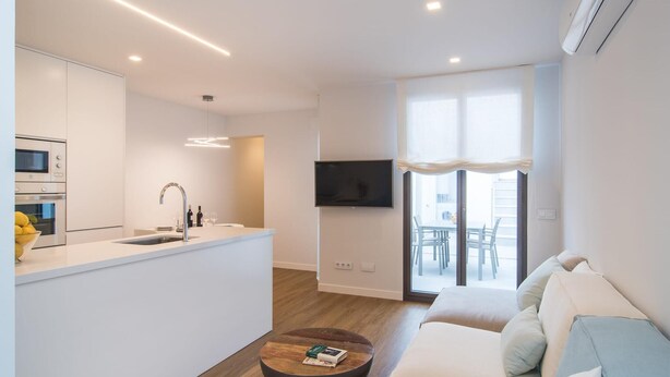A modern kitchen with built-in appliances, a dining area with a table and chairs, and a living room with a sofa and a coffee table. - 2 bedroom luxurious apartment in SIllot Cala Morlanda (SIllot Cala Morlanda)