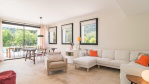 Ein modernes Wohnzimmer mit einem weißen Sofa, einem beigen Sessel und einem Essbereich mit Tisch und Stühlen.