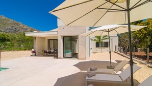 Ein moderner Außenbereich mit Pool, Liegestühlen und Sonnenschirmen.