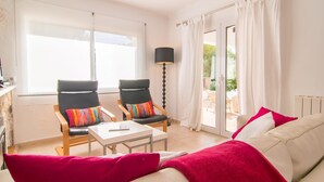 A bright living room with two black armchairs, a white sofa, a small table, and a floor lamp.
