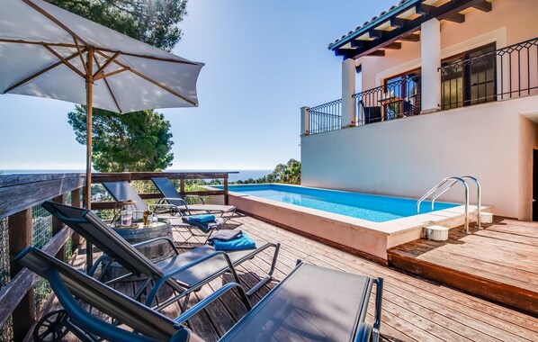 A poolside area with lounge chairs, a wooden deck, and a view of the ocean. - Stunning home in Canyamel with private swimming pool, can be inside or outside (Canyamel)
