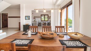 Een eetgedeelte met een houten tafel, stoelen en een keuken op de achtergrond.