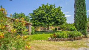 A rustic house with a well-maintained garden, stone walls, and a large tree. - Casa S'Era de Costitx (Costitx)
