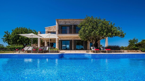 Ein zweistöckiges Haus mit einem Pool davor.