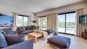 Ein modernes Wohnzimmer mit einer Couch, einem Couchtisch und Blick auf einen Swimmingpool.