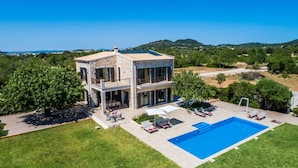 Ein zweistöckiges Steinhaus mit Swimmingpool, Außenbereich zum Sitzen und Blick auf die umliegende Landschaft.