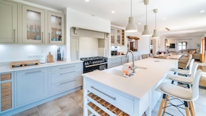 A modern kitchen with a central island, built-in appliances, and a dining area with bar stools. - Cozy home in Andratx with private swimming pool, can be inside or outside (Andratx)