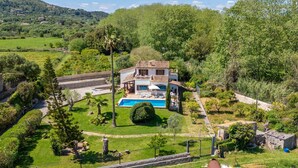 Eine Villa mit Swimmingpool, umgeben von üppiger Vegetation und Hügeln.