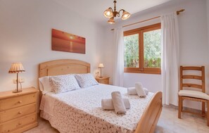 Ein Schlafzimmer mit einem hölzernen Bett, zwei Nachttischen, einem Schminktisch, einem Stuhl, einem Fenster mit Vorhängen und einem Gemälde an der Wand.
