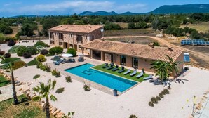 Eine Villa mit Swimmingpool, Sitzgelegenheiten im Freien und Blick auf die umliegende Landschaft.