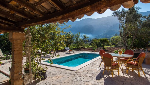 Ein Poolbereich mit Pergola, Sitzgelegenheiten und Blick auf Berge.