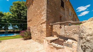 Un edificio de piedra con piscina y un banco de piedra.