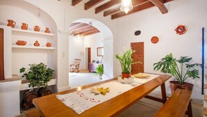 Un comedor con mesa de madera, plantas en macetas y macetas de barro en estantes.