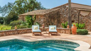 A stone building with a tiled roof, a swimming pool, and two light blue lounge chairs. - Cozy home in Santanyi with private swimming pool, can be inside or outside (Santanyi)