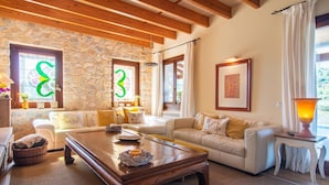 A cozy living room with stone walls, wooden beams, a white sofa set, and a wooden coffee table. - Nice home in Arta with private swimming pool, can be inside or outside (Arta)