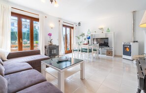 Un salon moderne comprenant un canapé, une table basse en verre, une cheminée et un coin repas avec des chaises et une table.