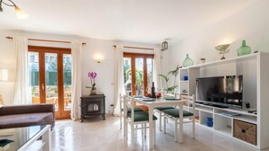 Un soggiorno moderno con camino, angolo pranzo con sedie verdi, televisore e un'ampia finestra con tende.