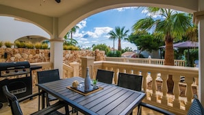 Eine Terrasse im Freien mit einer Steinmauer, einem Grill und einem Tisch mit Stühlen.