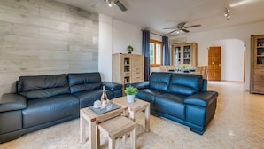 Ein modernes Wohnzimmer mit zwei schwarzen Ledersofas, einem Holztisch und einem Deckenventilator.