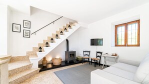 Un salon moderne avec un escalier blanc, une cheminée, un canapé et un téléviseur fixé au mur.